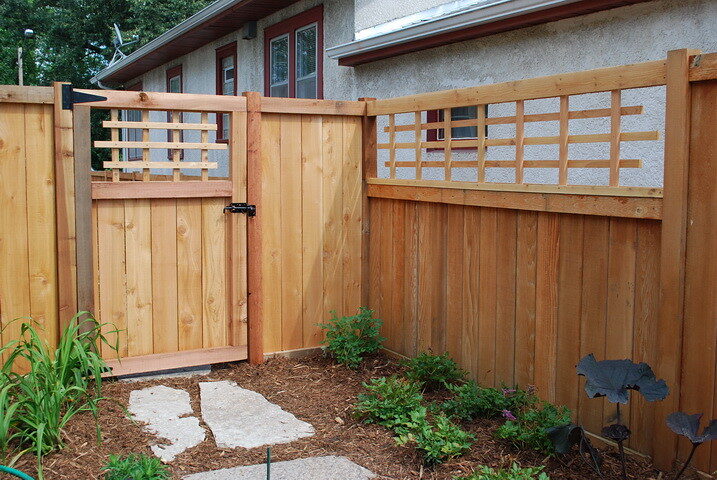 New cedar privacy fence with a matching gate and lattice top in a residential backyard, shown as a style example of wood fencing